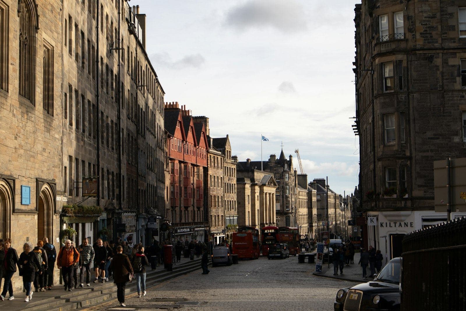 Crowds walking down Edinburgh's Royal Mile past historic Old Town buildings under an overcast sky. Photo by Wyatt Simpson on Unsplash (unsplash.com/photos/IkXsGVIWcpk)